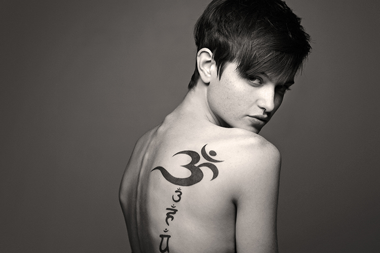 Person with a short haircut showing a large tattoo on their back in black ink.